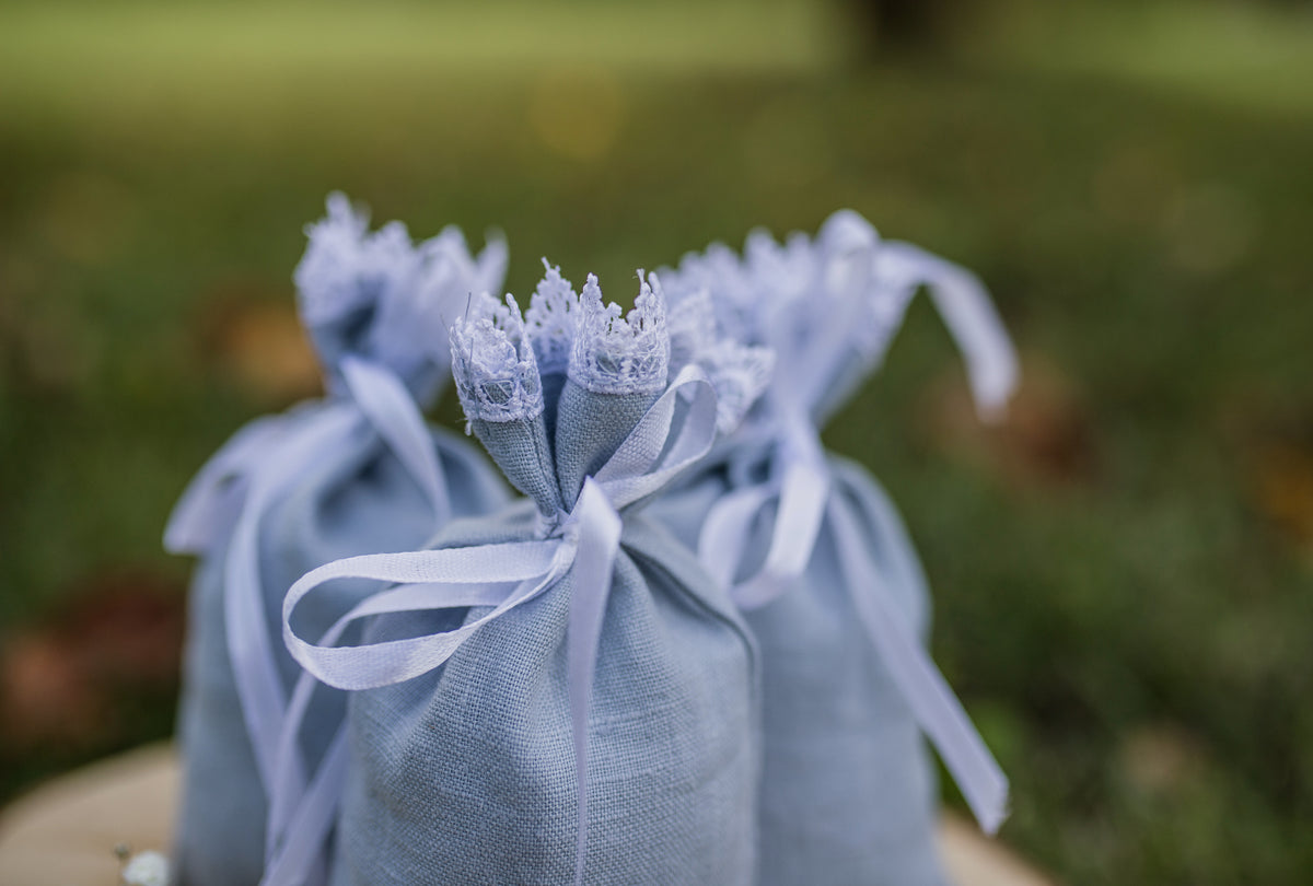 Three light dusty linen gift bags tied with matching white ribbon,