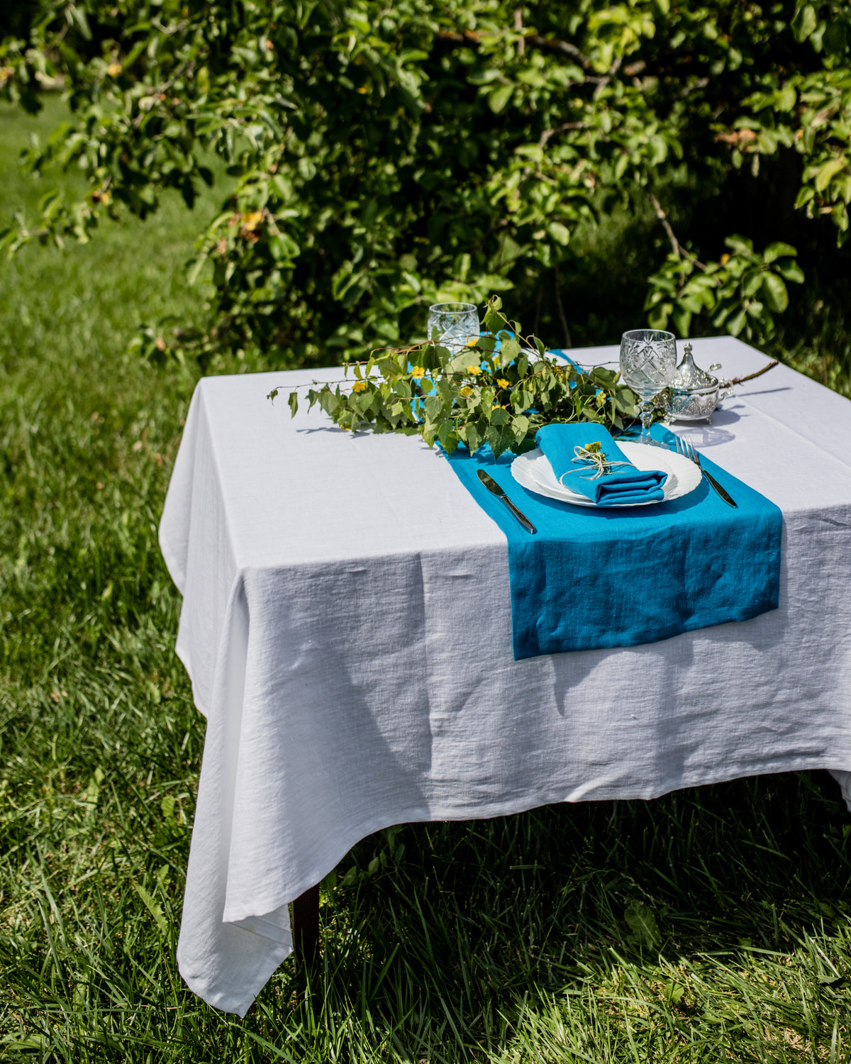 Set table with Turquoise runner and white tablecloth outdoors