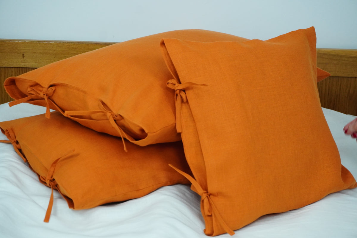 Orange pillows on a bed with a wooden headboard.