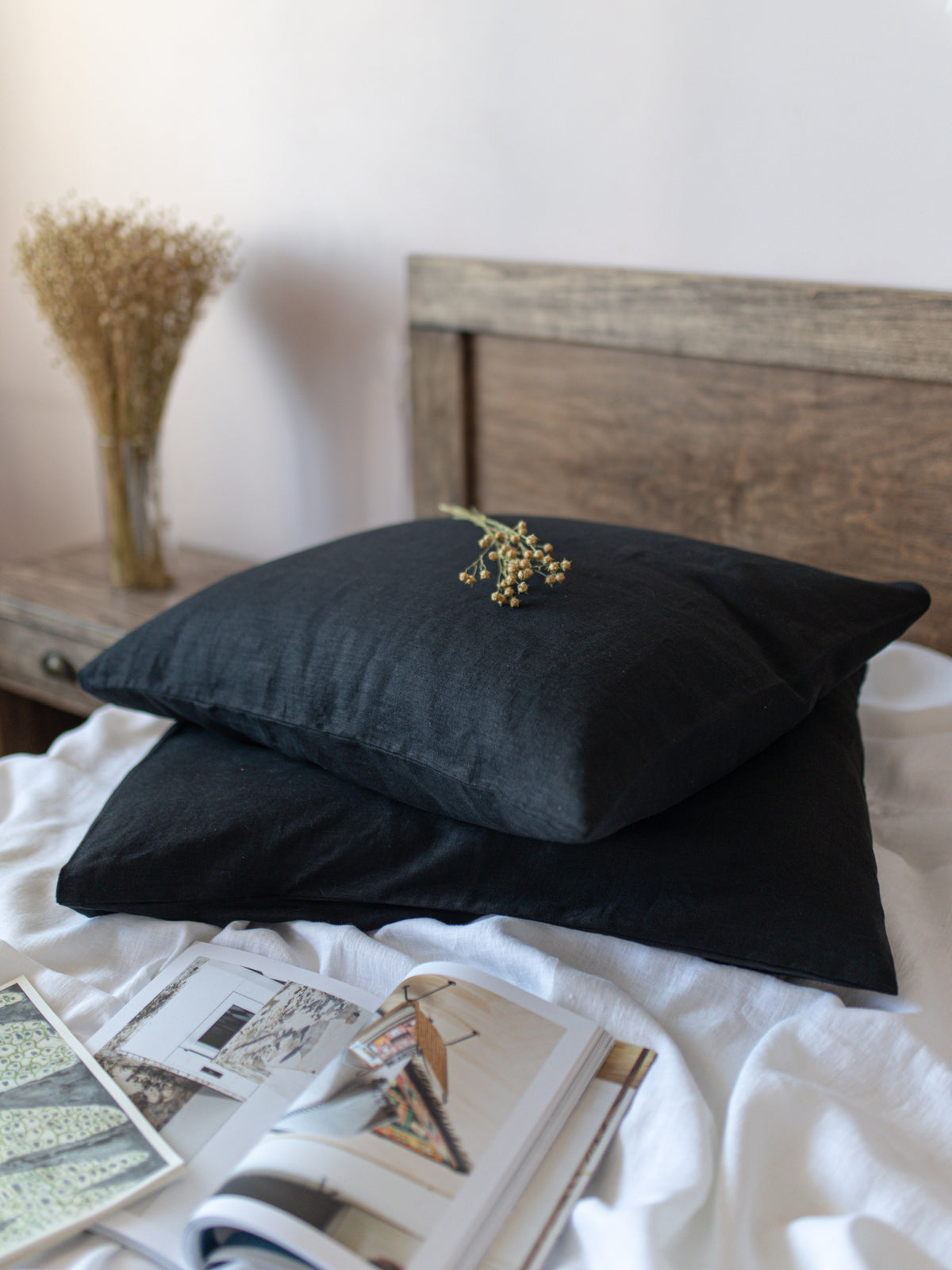 Black pillows on a bed with a wooden headboard and decorative items.