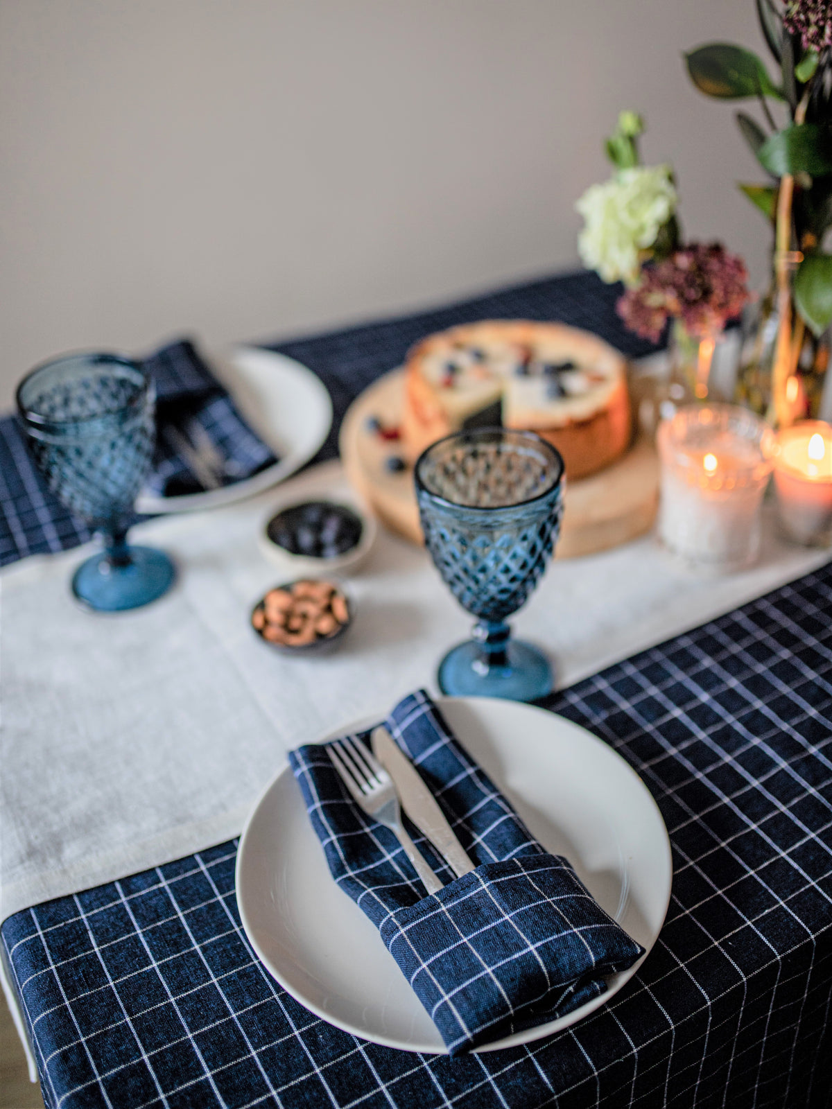 Dining table setting with blue checkered napkins, white plates, and decorative items.