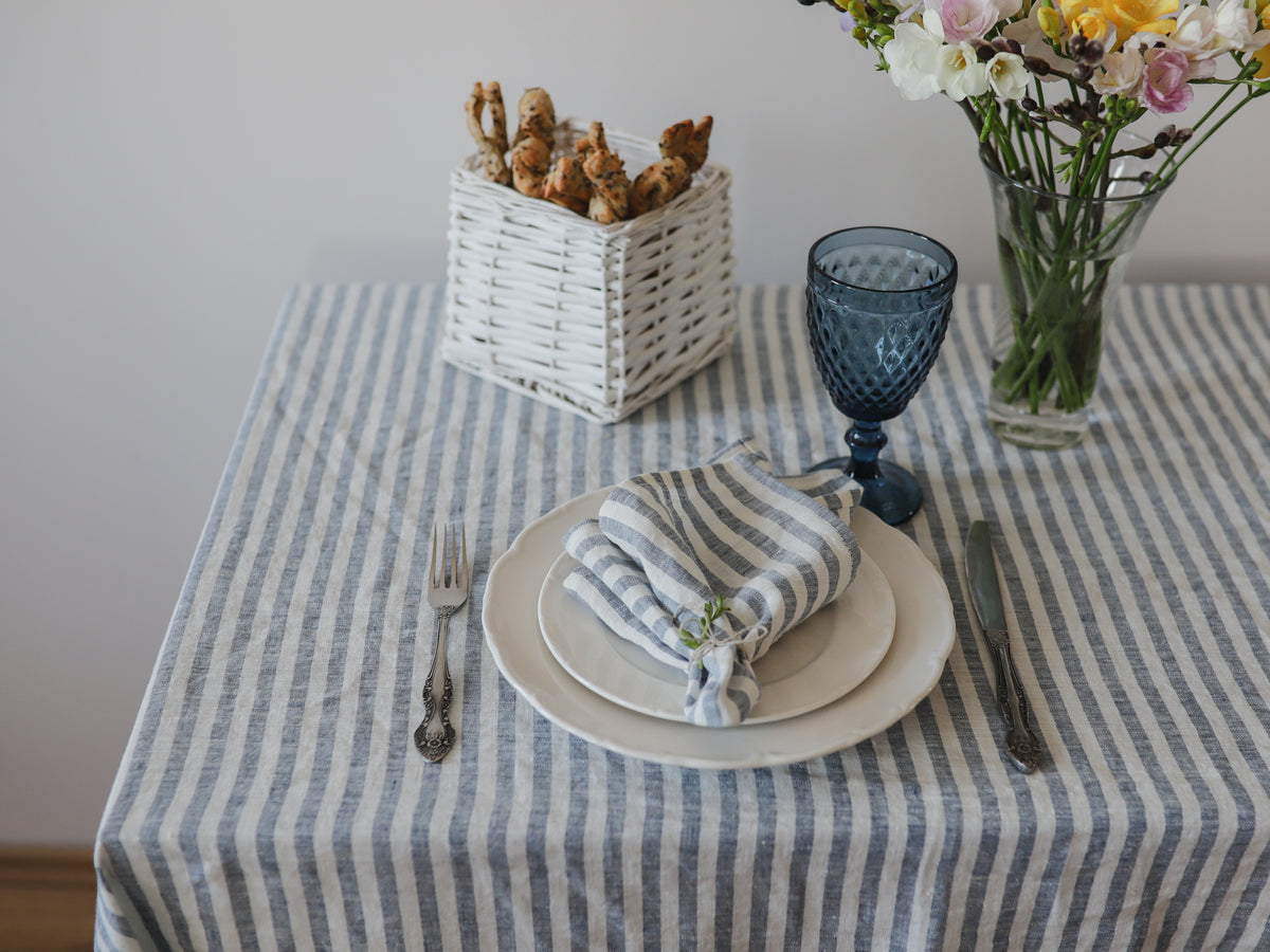 Dining table setting with striped linen napkin, plates, cutlery, and decorative elements.