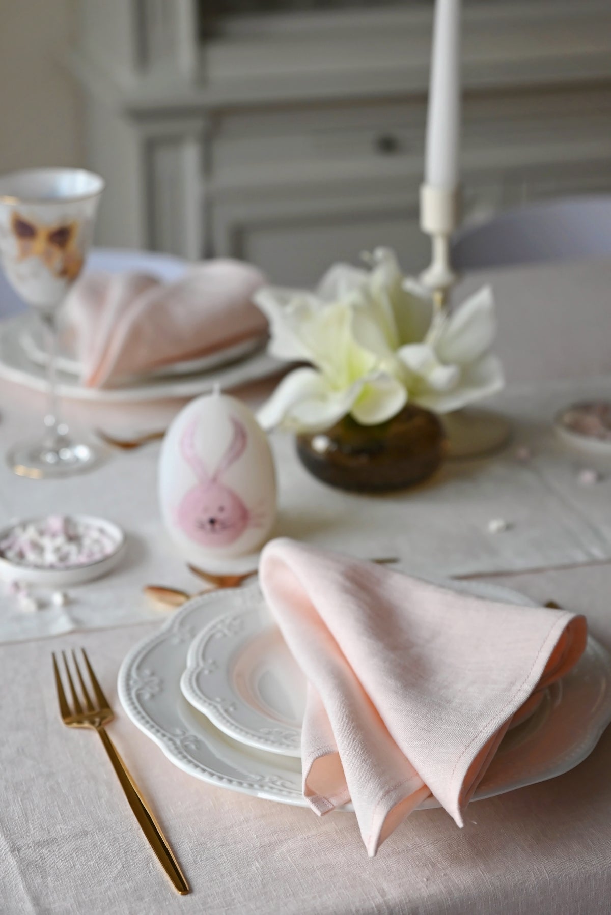 Easter table setting with pastel colors, including pink eggs and blush pink  napkins.