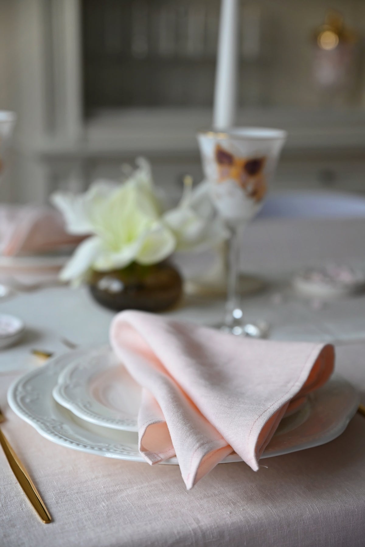 Table setting with blush pink napkin, plates, and flowers