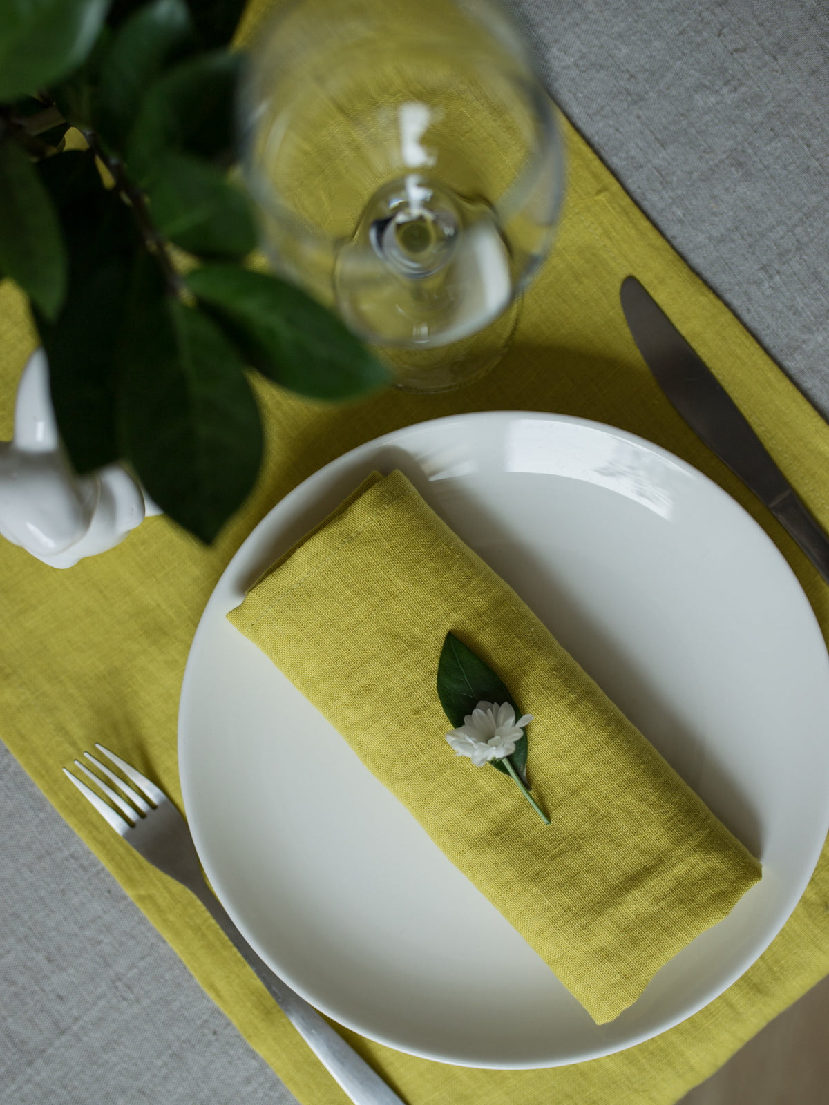 Table setting with a white plate, chartreuse linen fabric napkin, and green placemat.