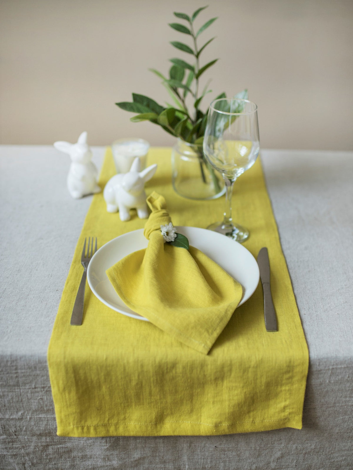 Chartreuse table runner with white plates, napkins, and decorative elements on a neutral background