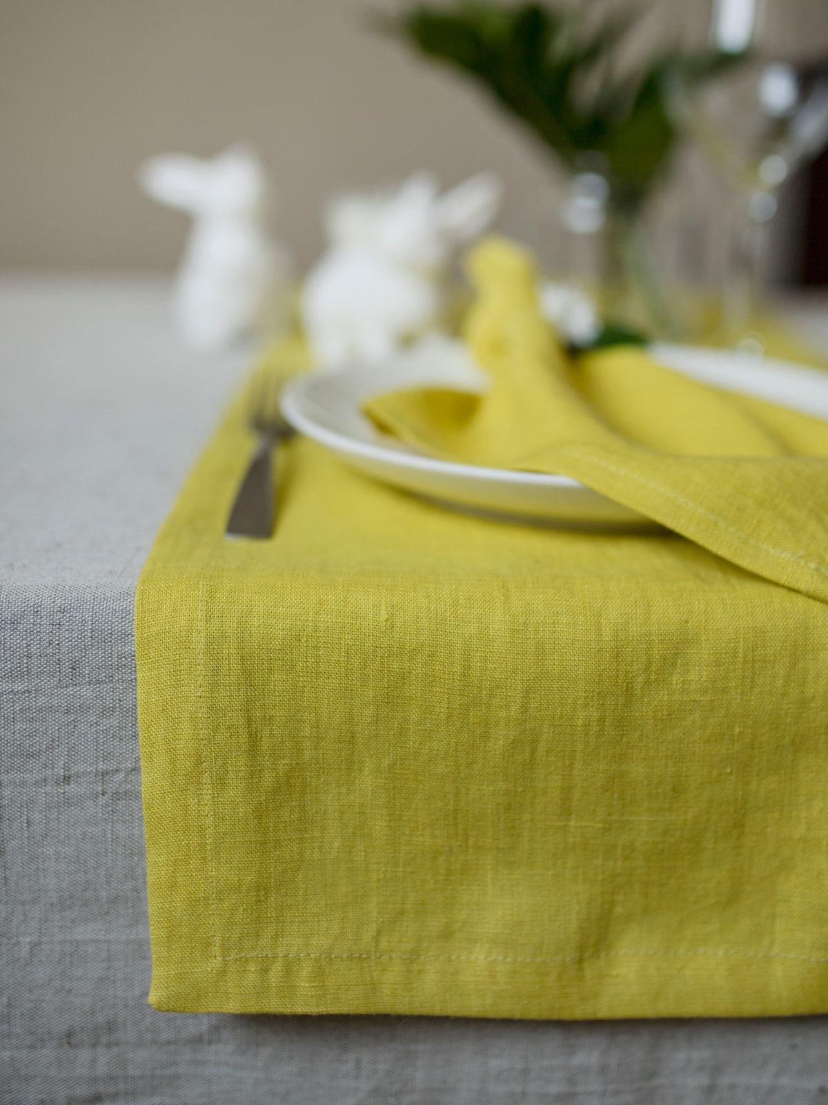 Chartreuse table runner on a gray tablecloth with white plates and silverware.