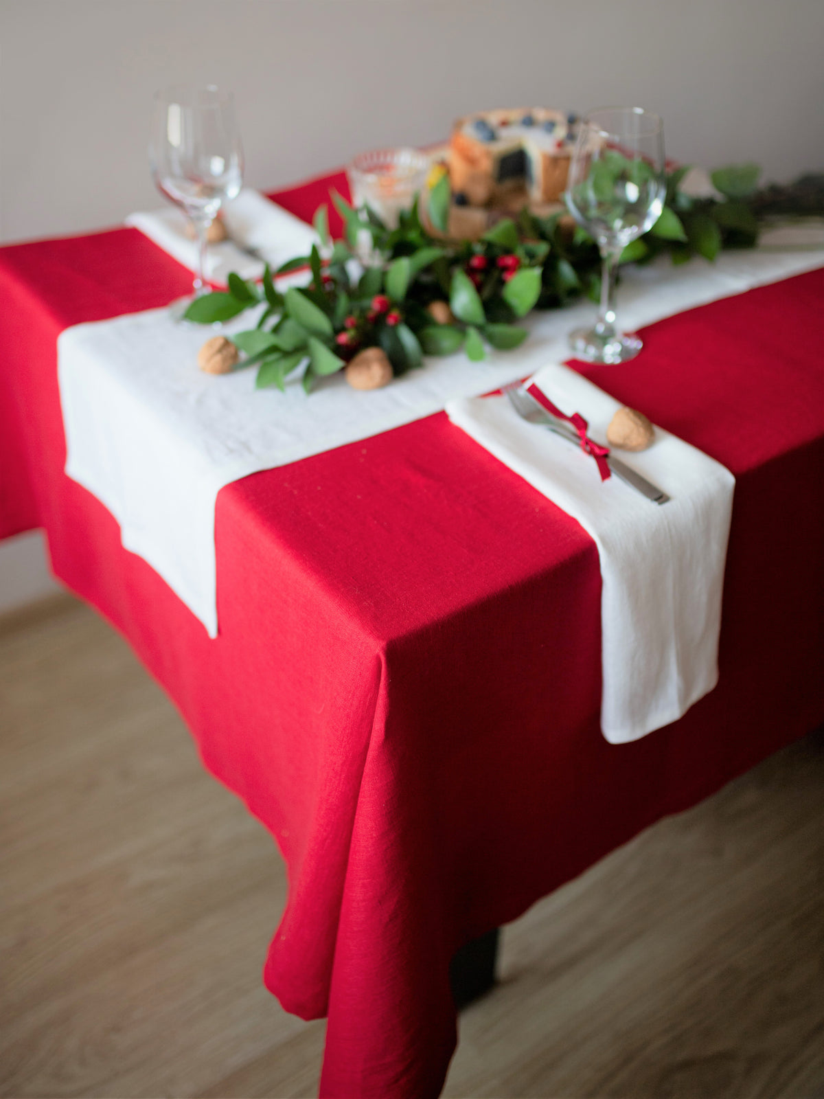 Decorated table with red linen tablecloth, white napkins, and greenery.