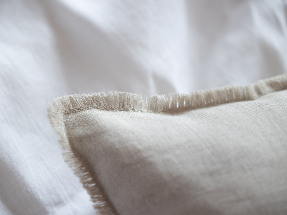 Close-up of a textured natural linen pillow on a white background