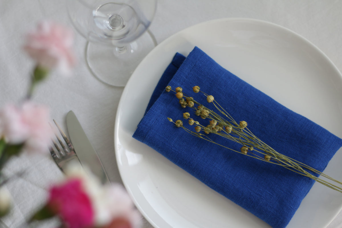 Table setting with a royal blue napkin, white plate, and floral decorations.
