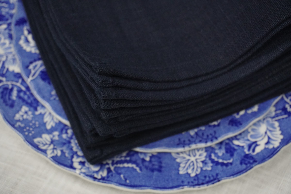 Stack of navy blue linen napkins  on a blue floral-patterned surface