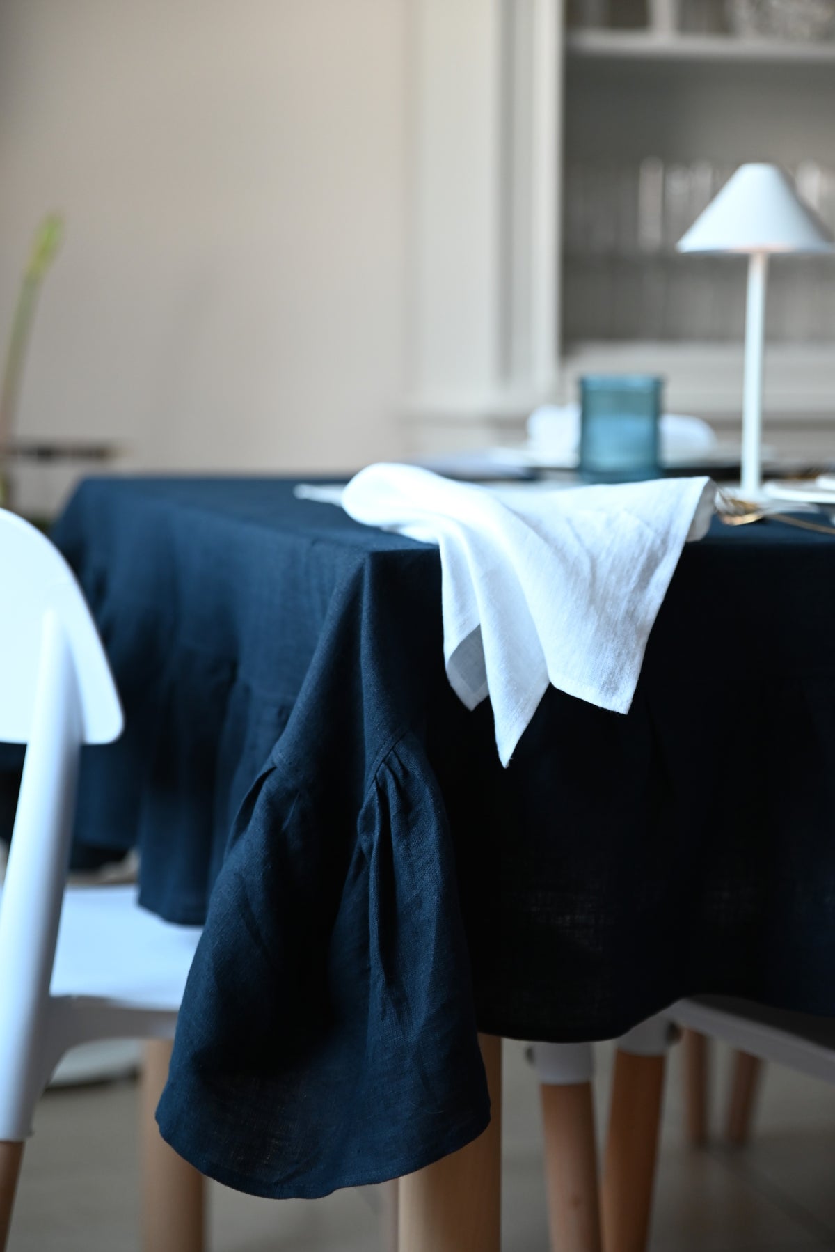 Navy blue linen tablecloth on a table with white napkin in a softly blurred room setting