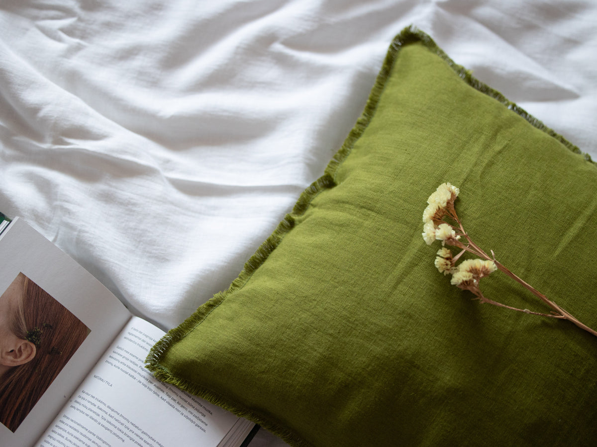 Moss Green pillow with flowers on a white bed