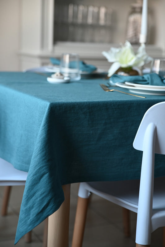 Teal/patina blue linen  tablecloth on a dining table with white chairs and