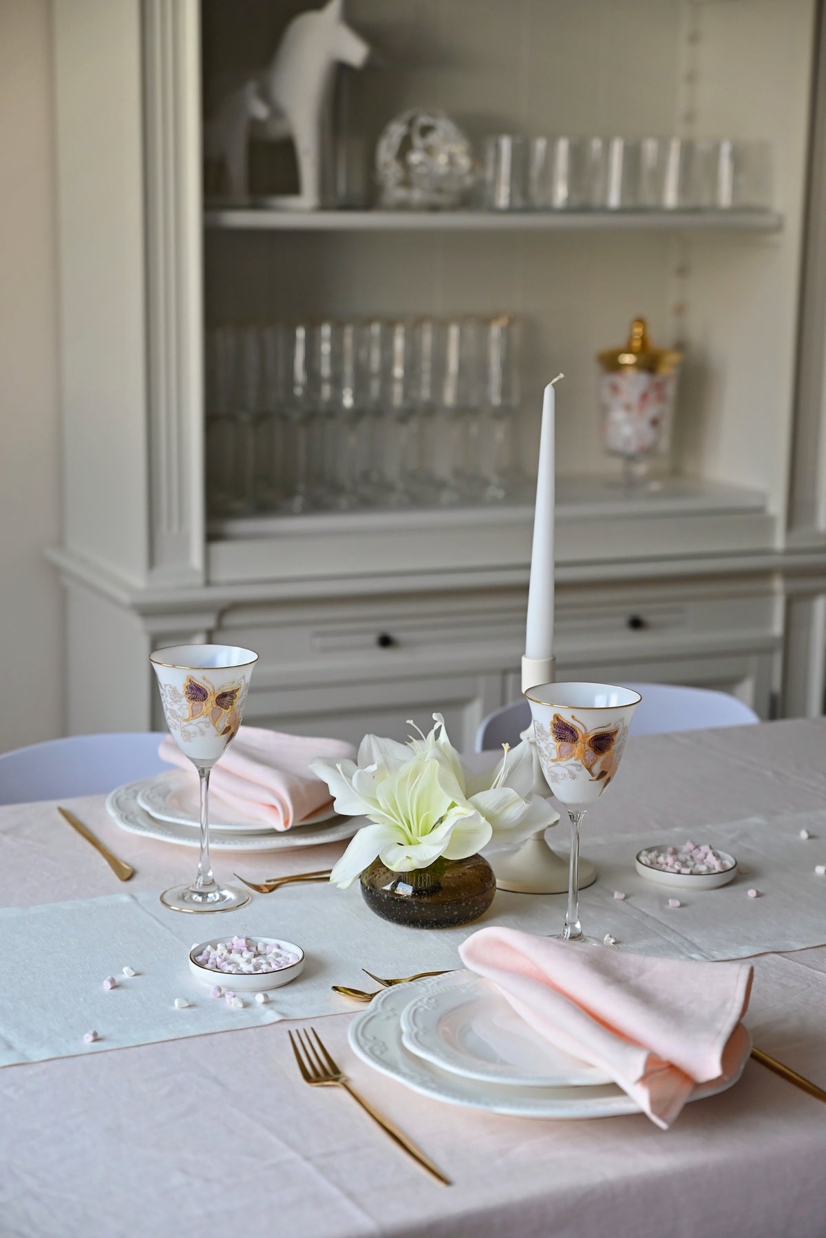 Elegant pink  linen tablecloth,  setting with floral centerpieces and glassware in a softly lit room.