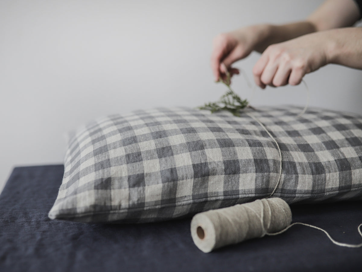A girl  arranging dried herbs on a plaid linen pillow with a roll of yarn beside it.
