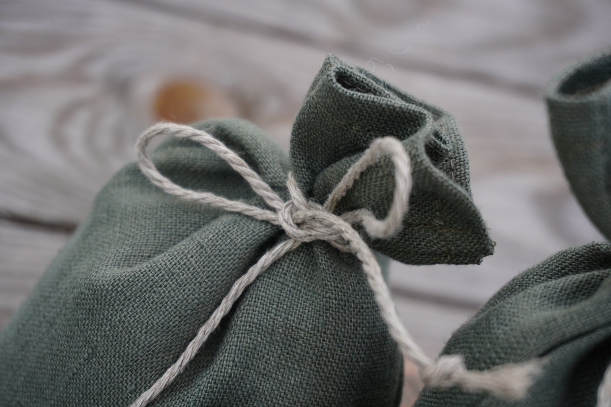 A close-up of a sage green linen pouch tied with a white twine bow