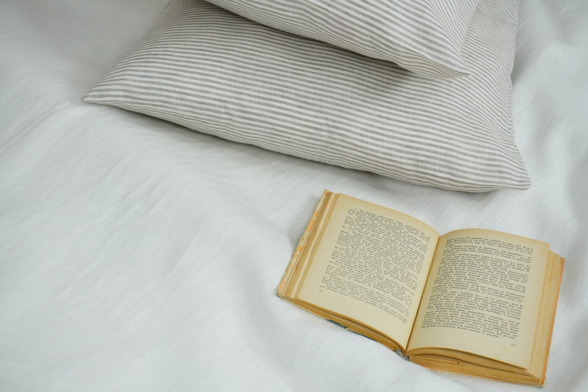 Open book on a bed with striped pillows