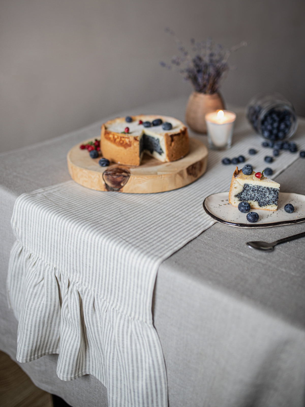  a striped linen table  runner, candles, dried lavender, and scattered blueberries.