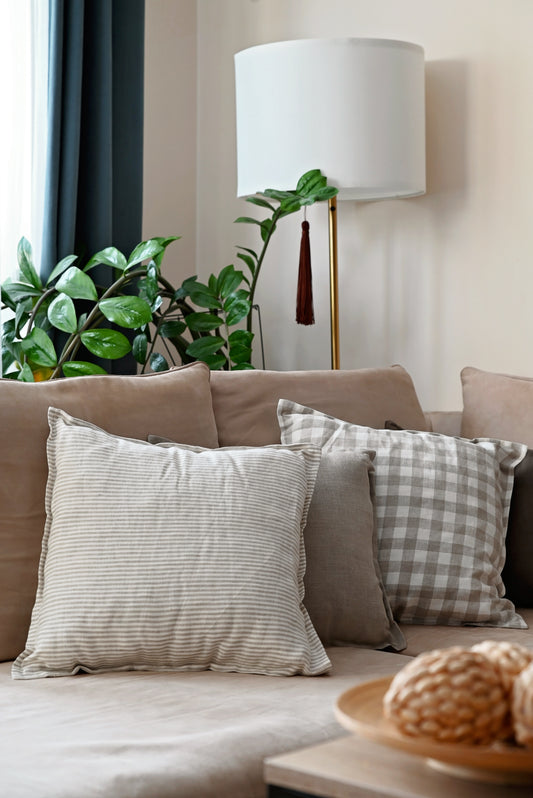 Decorative  linen pillows on a couch with a lamp and plants in the background