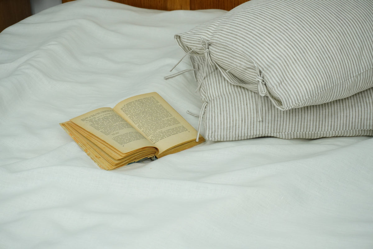 Open book on a bed with striped pillows