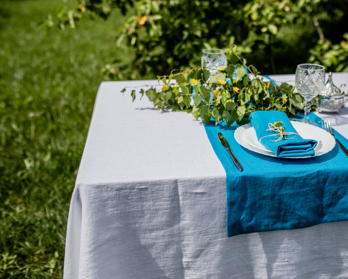 Table setting with blue napkins and white plates outdoors on a grassy background