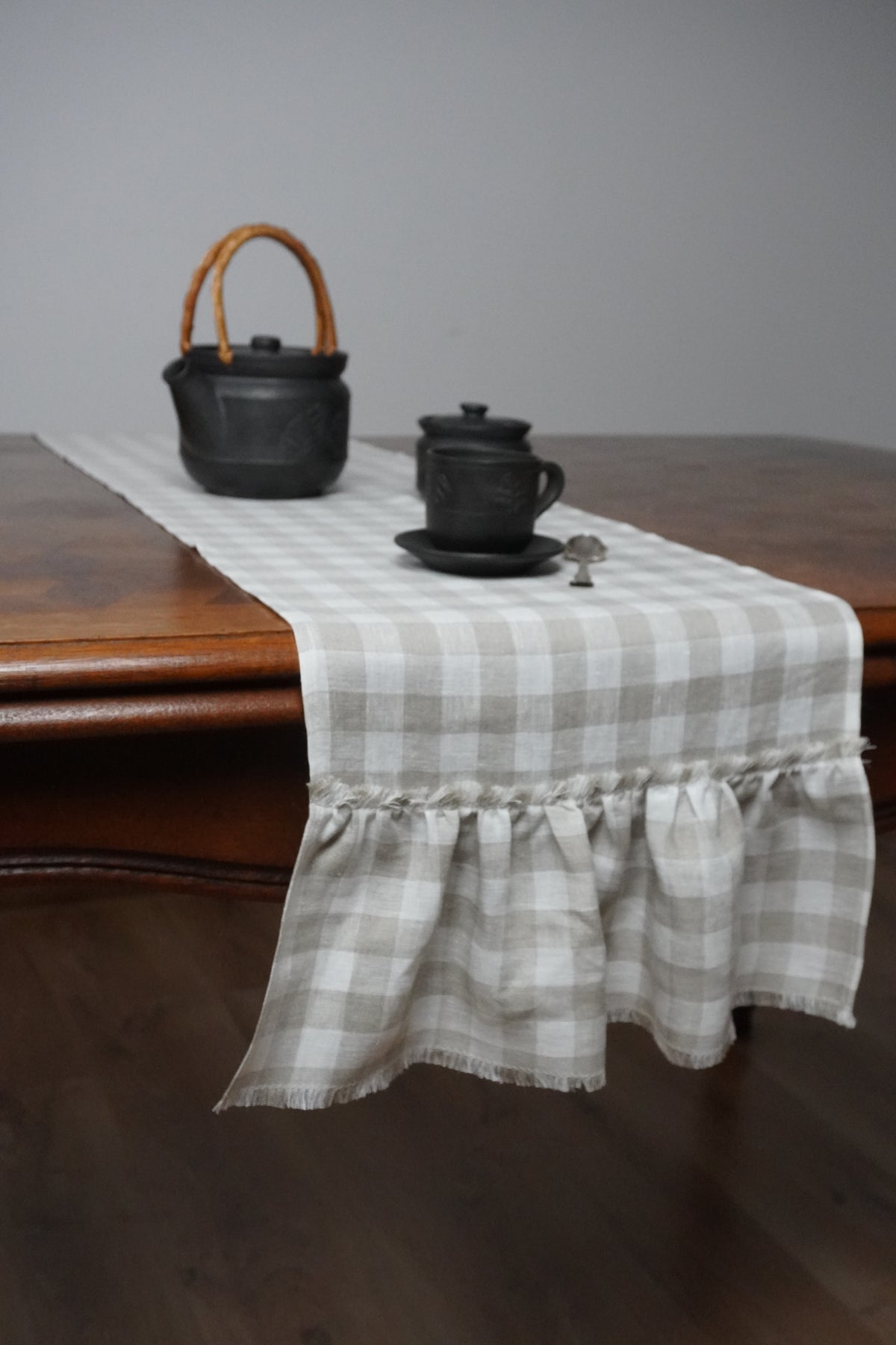 Plaid table runner with ruffles on a wooden surface
