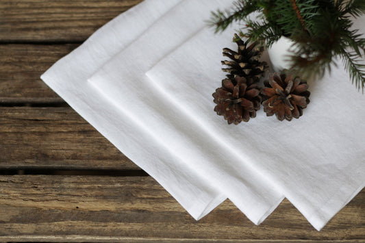 White linen napkins with pine cones and branches on a wooden surface