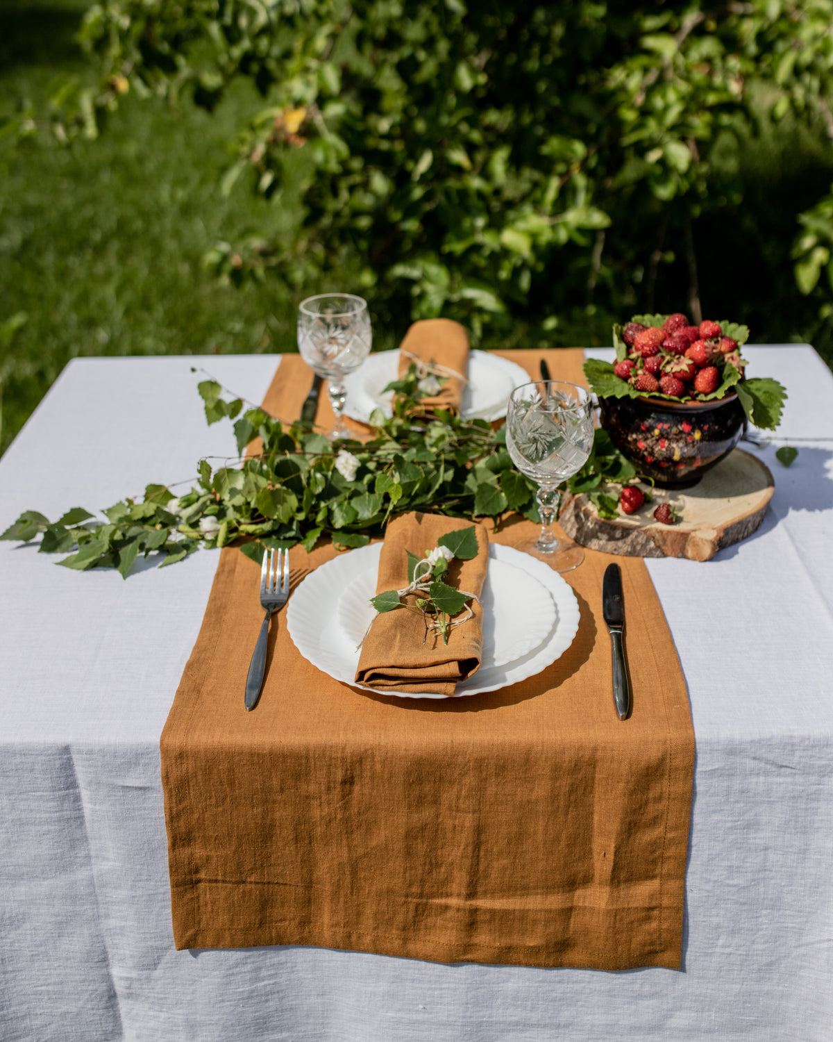 handmade mustard linen table runner in natural linen styled with plates and outdoor garden setting
