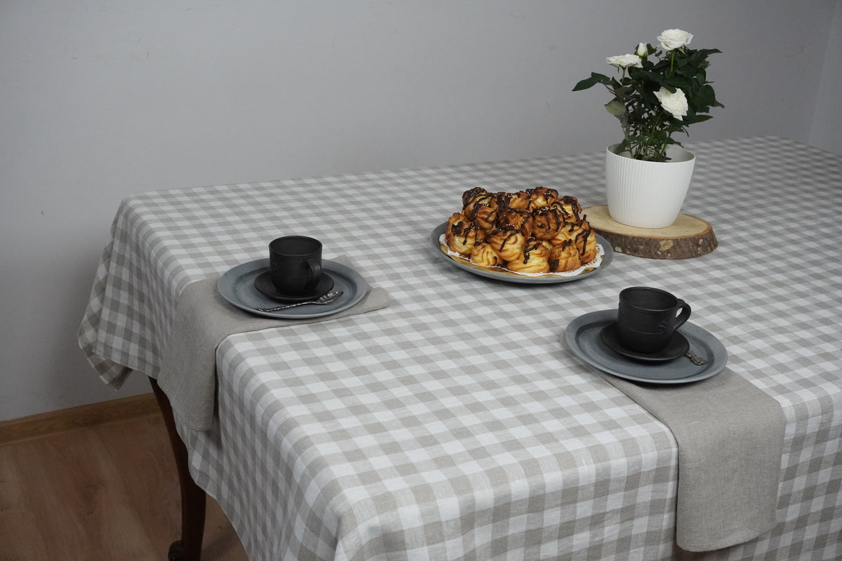 Table setting with checkered tablecloth, pastries, and cups on a plain background