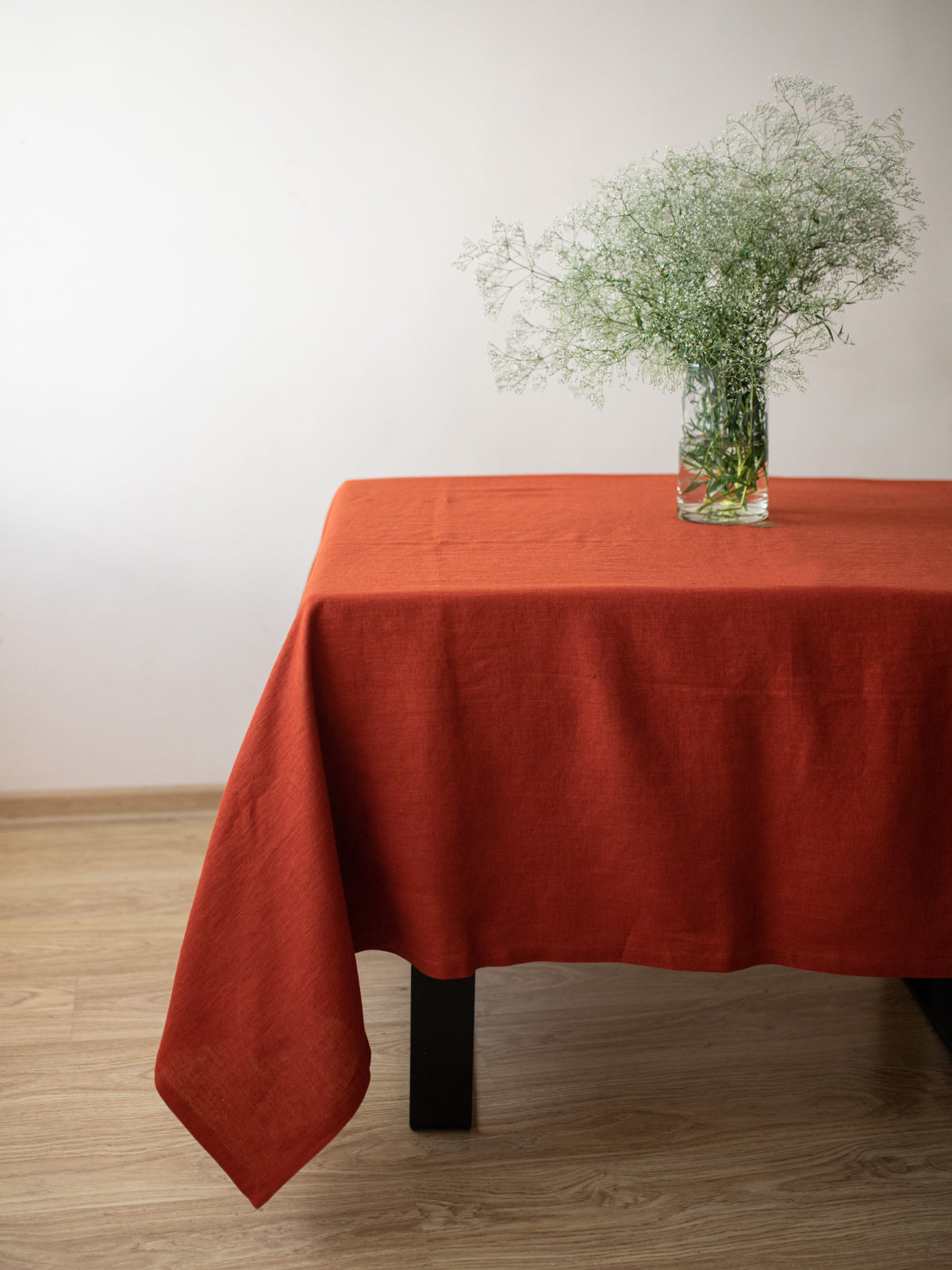 Handmade burnt orange linen tablecloth with natural flowers on a dining table