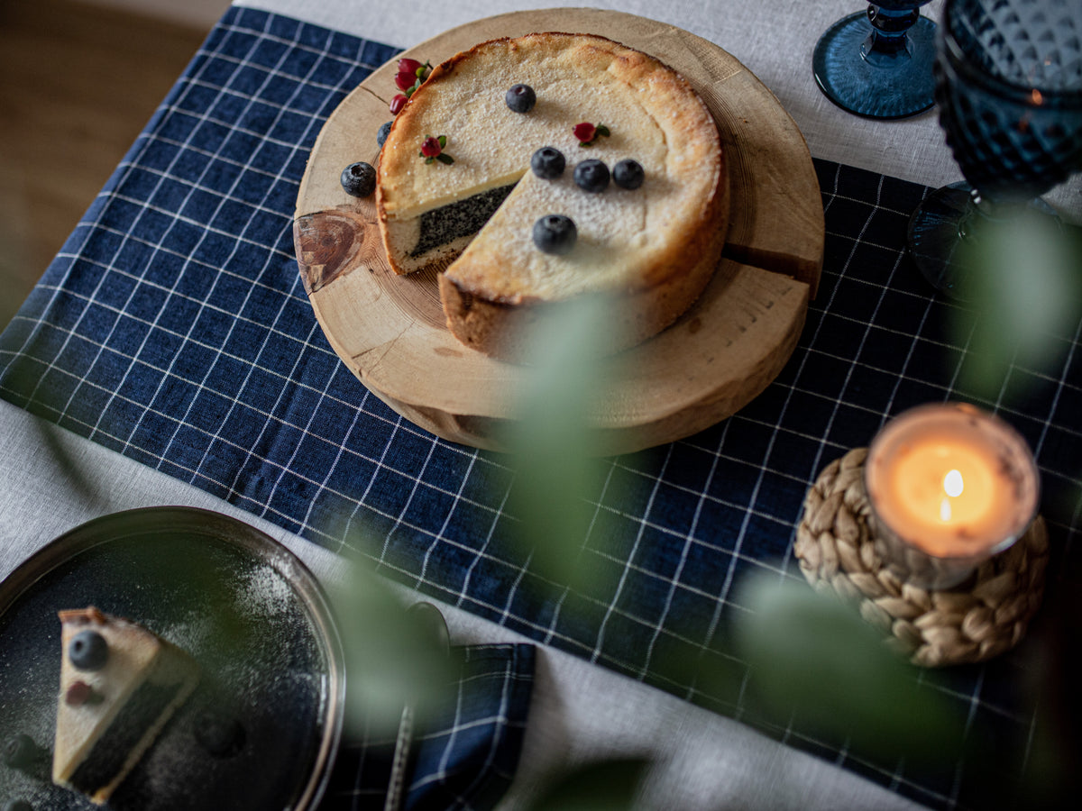 Pie on a wooden board with a candle and blue checkered table runner