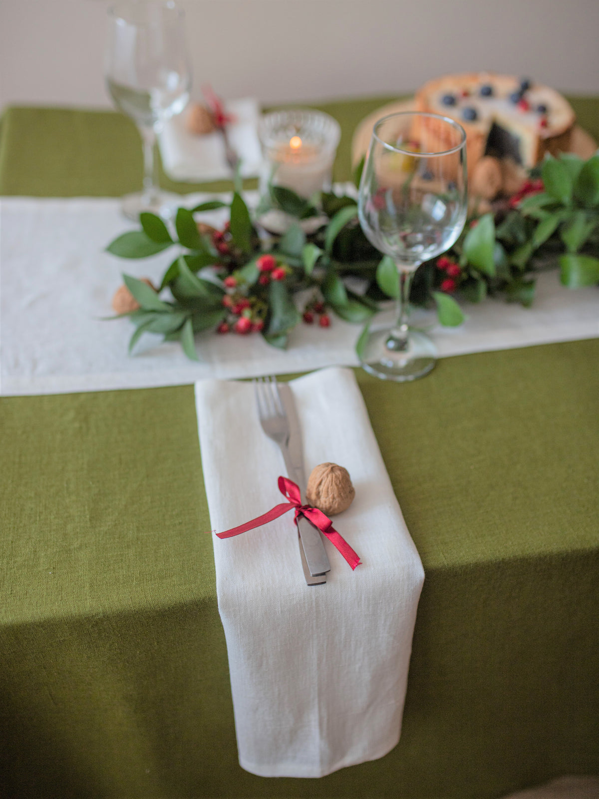 Handmade off white linen napkin styled with green tablecloth and natural holiday table decor