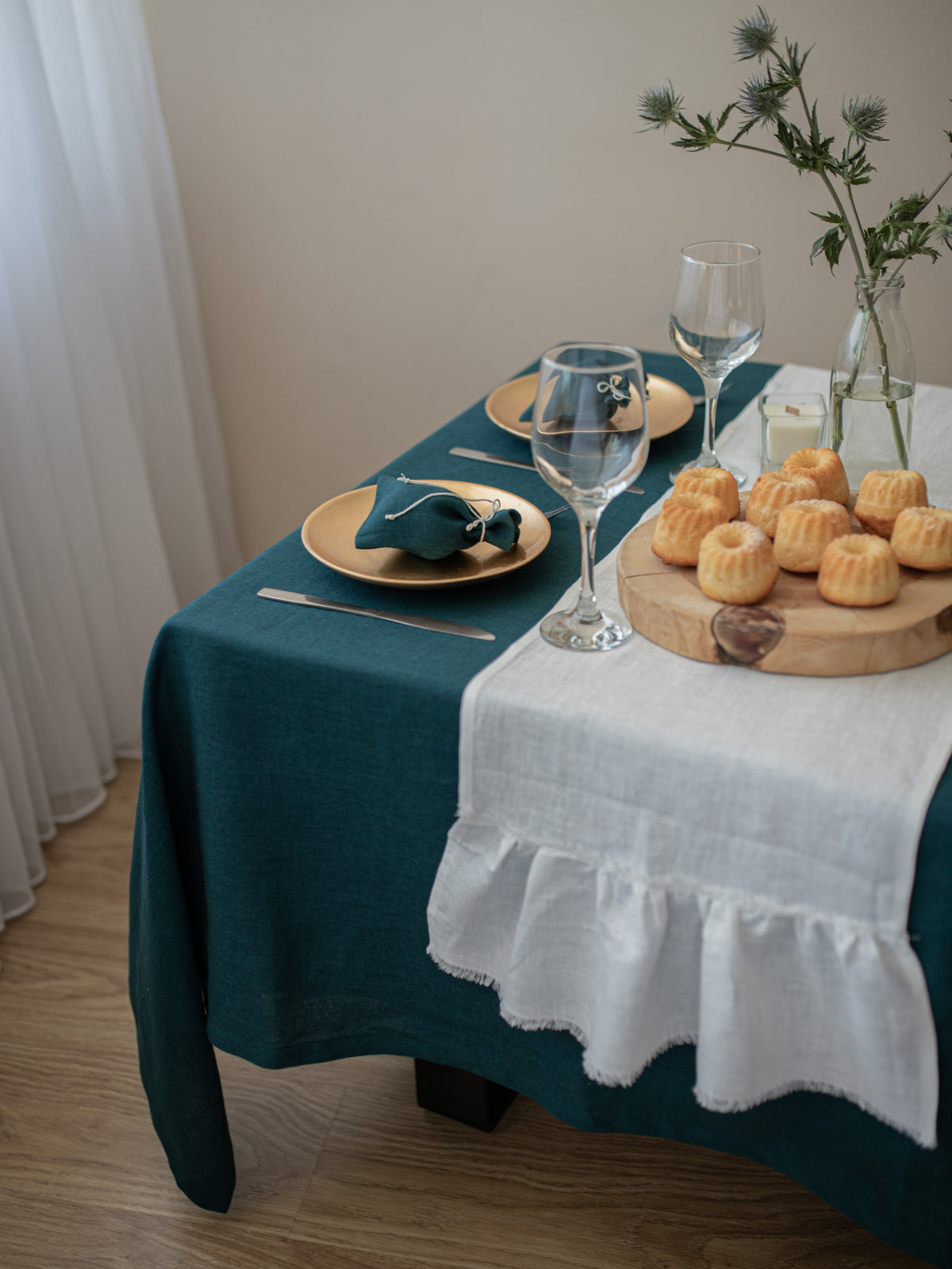 Dining table set with teal tablecloth, off white linen table runner.