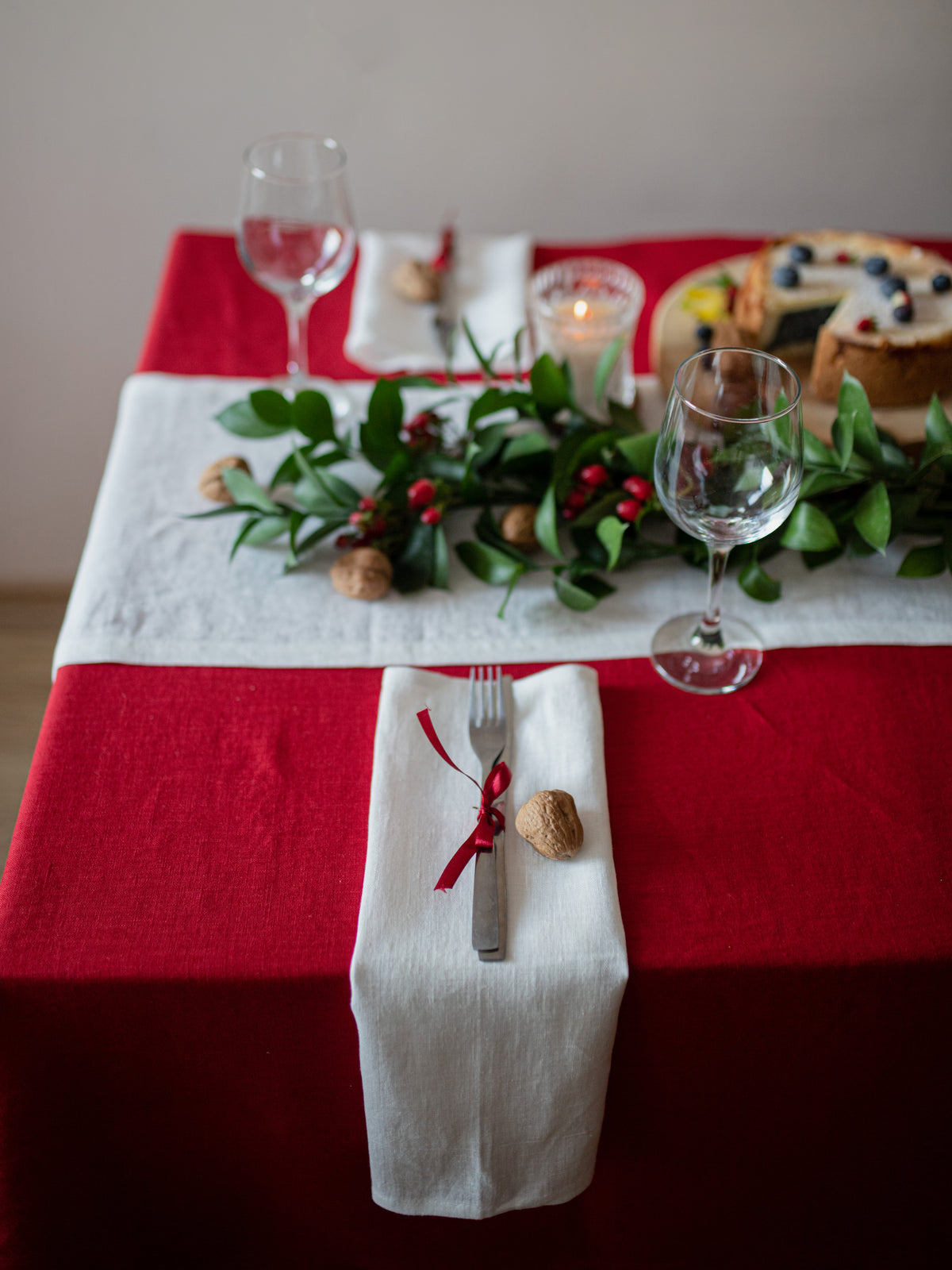 Off white linen napkins with red linen tablecloth and runner styled for an elegant Christmas table setting