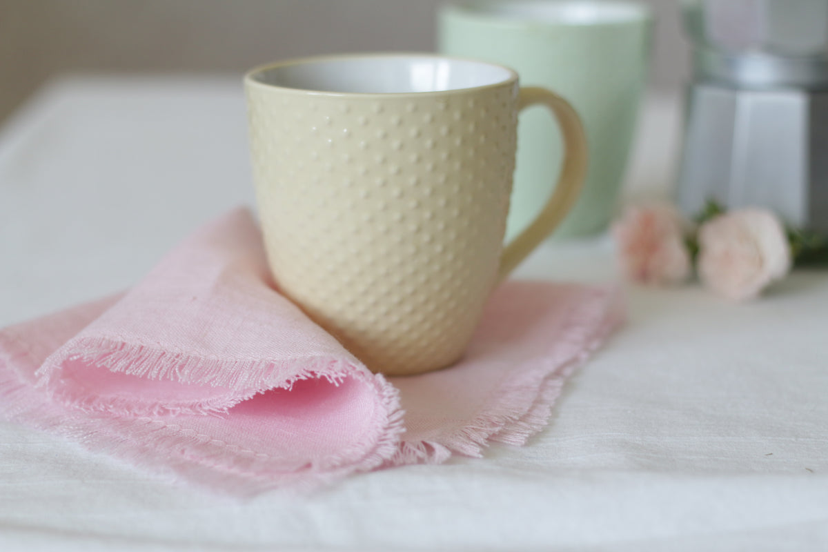 Beige textured mug on a pink linen napkin.