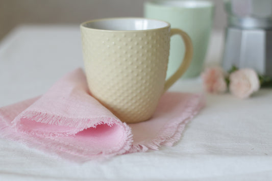 Beige textured mug on a pink linen napkin.