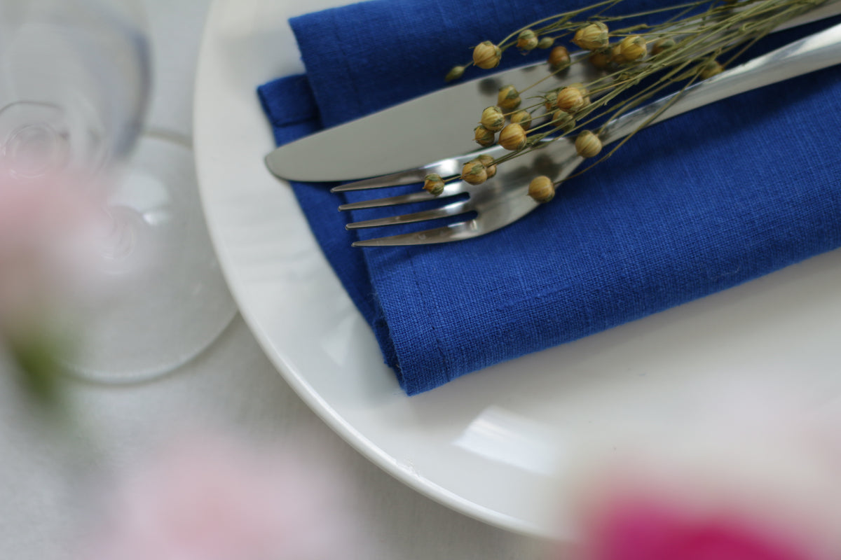 White plate with cobald blue napkin, silverware.