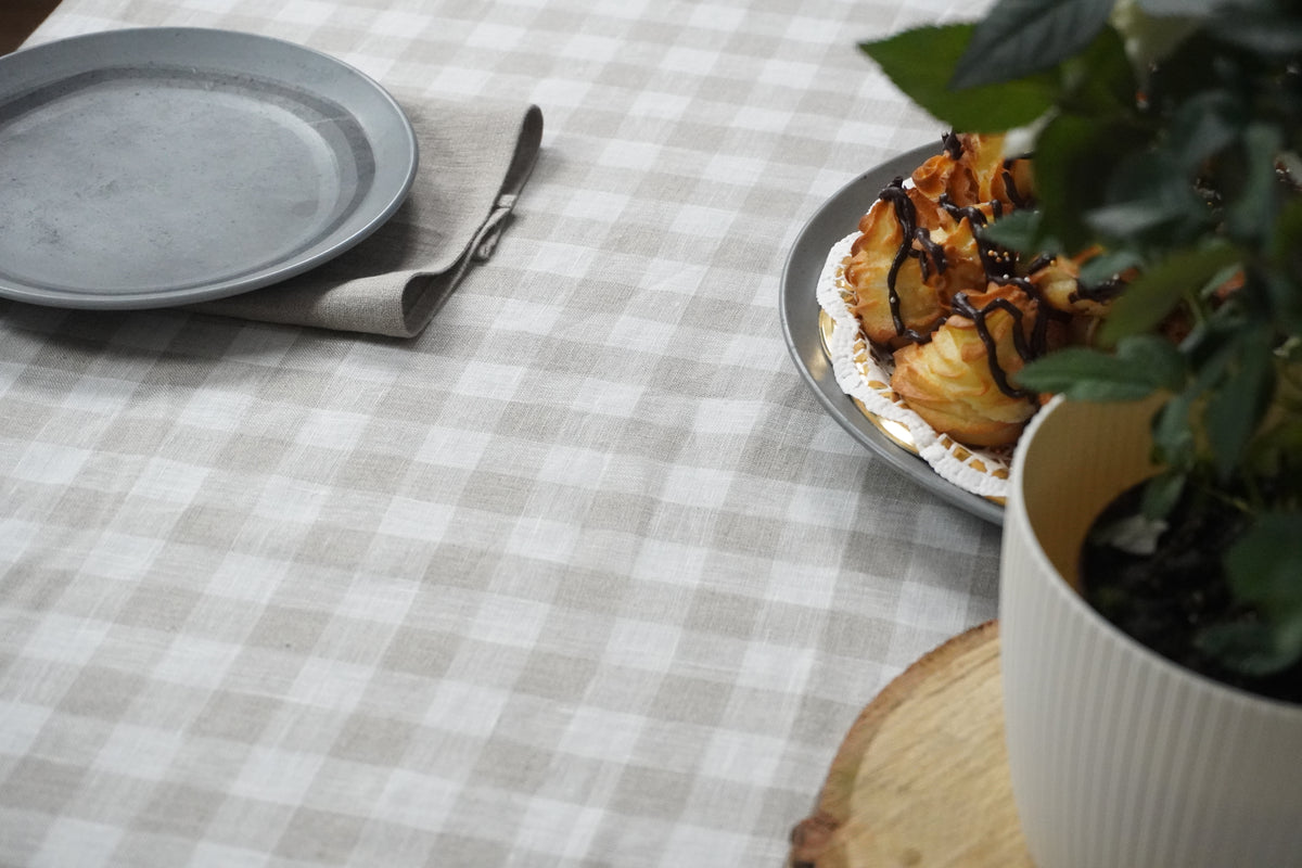 Table setting with gray plates, a plant, and a checkered gingham tablecloth.
