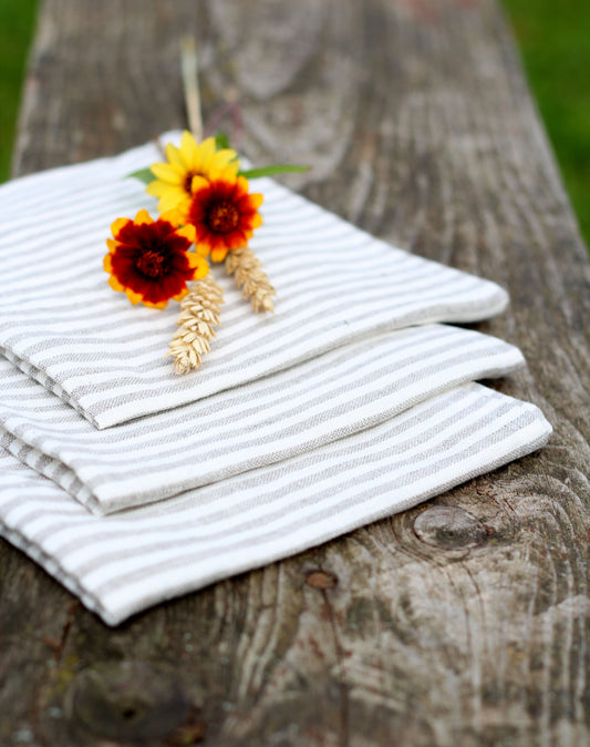 Stack of striped linen napkins with decorative flowers on a wooden surface
