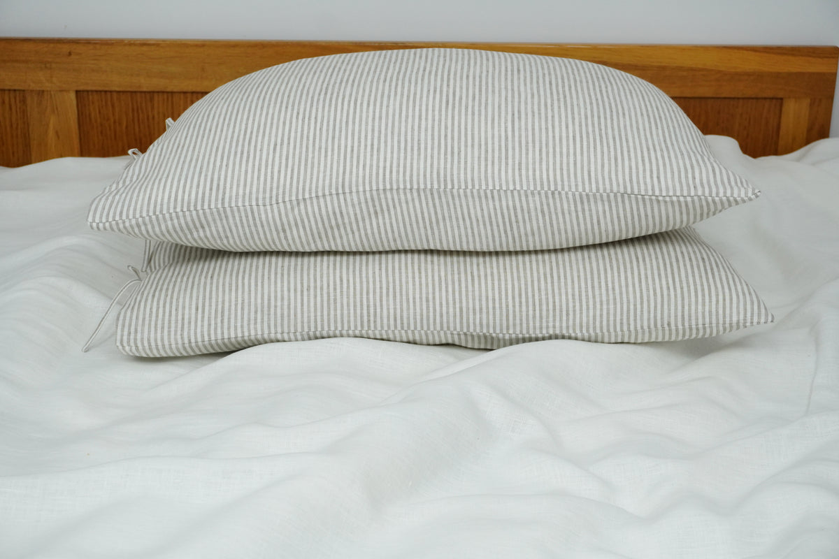 Two striped pillows on a bed with a wooden headboard.
