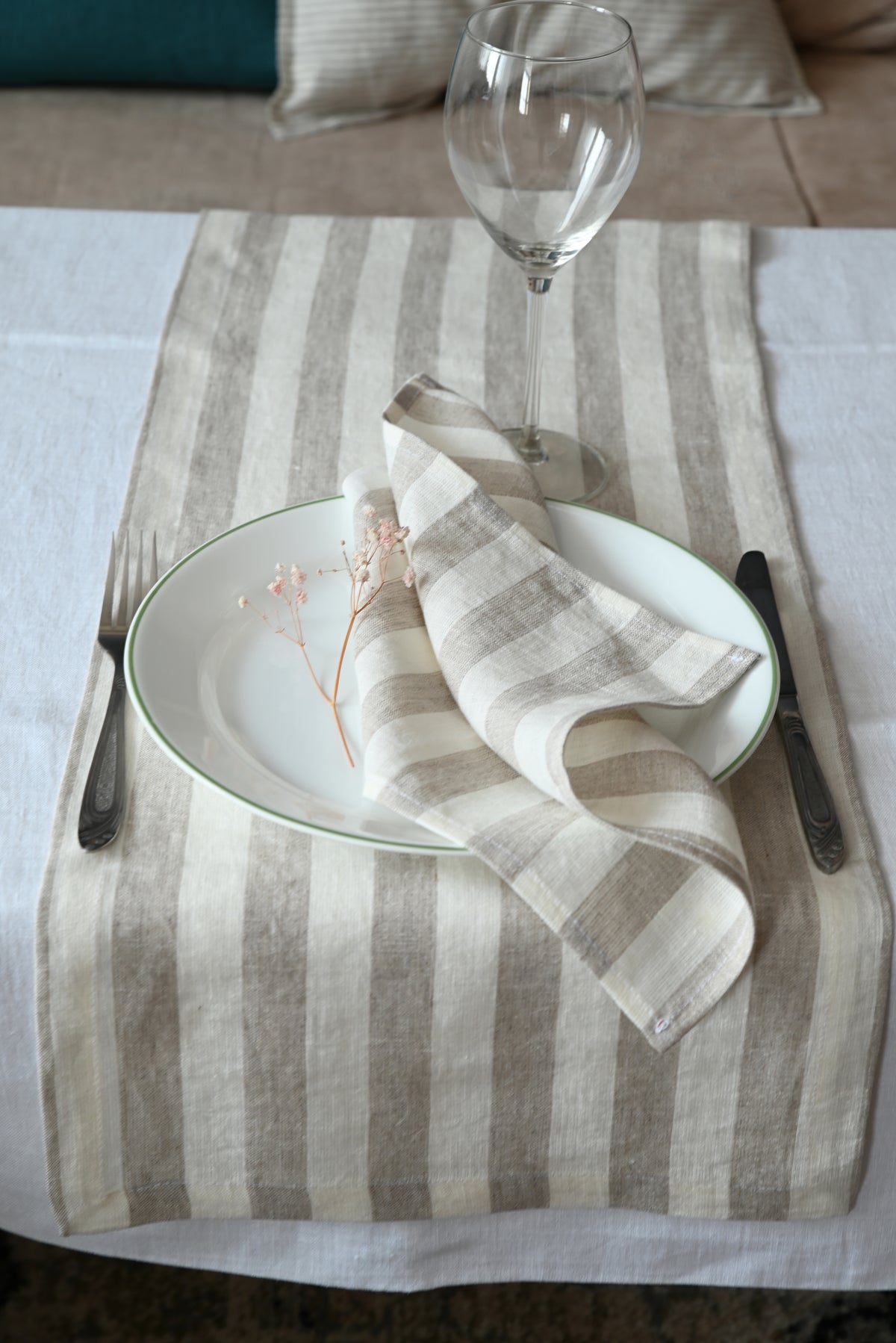Table setting with striped table runner, plate, napkin, and cutlery on a white surface.