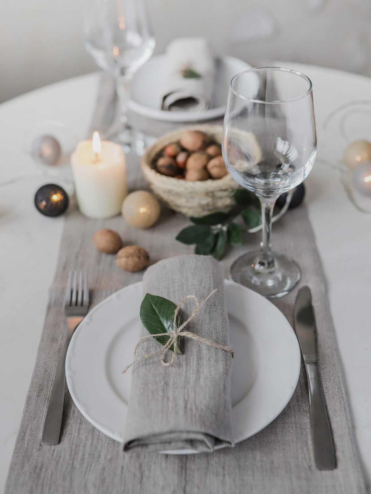 Easter table setting with eggs, candles, and a gray napkin on a white table.