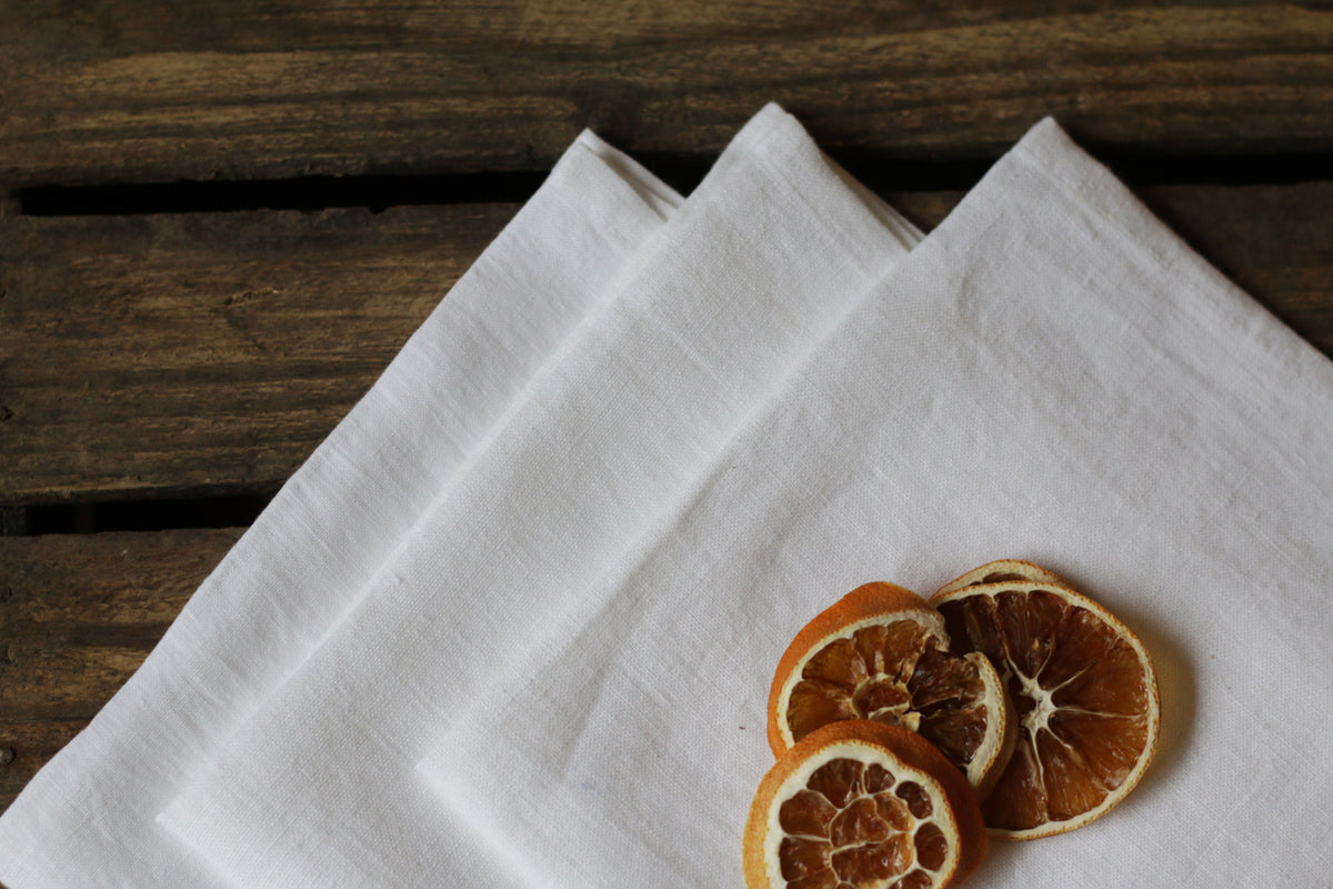 Three dried orange slices on a white linen napkin with a wooden background