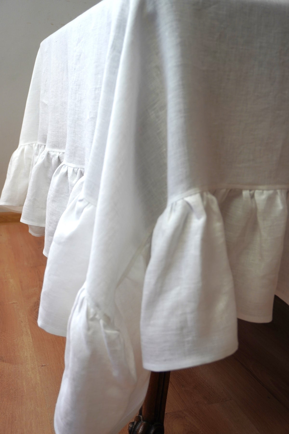 White linen  tablecloth with ruffles on a wooden table 